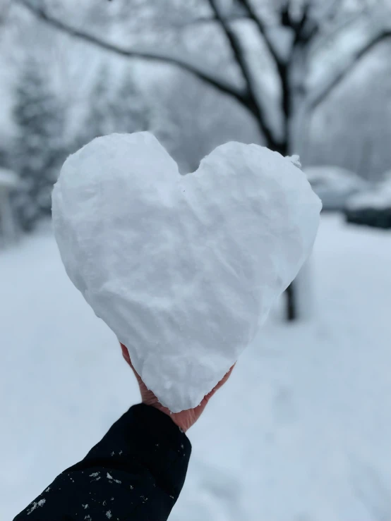 a snow heart being held in the snow