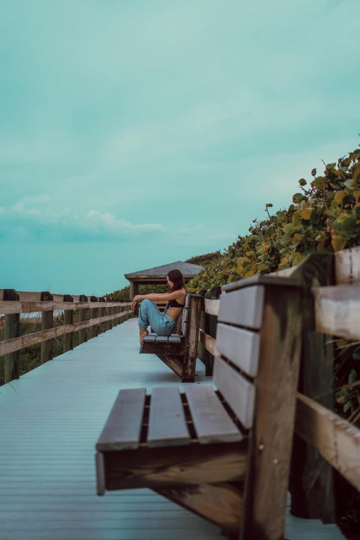 a woman sitting on a bench by the water