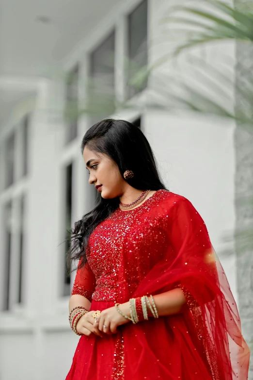 a woman in a red lehenga poses on the steps