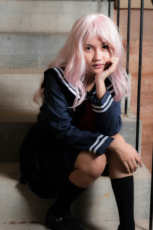 woman with long, pale hair sitting on steps while looking at camera