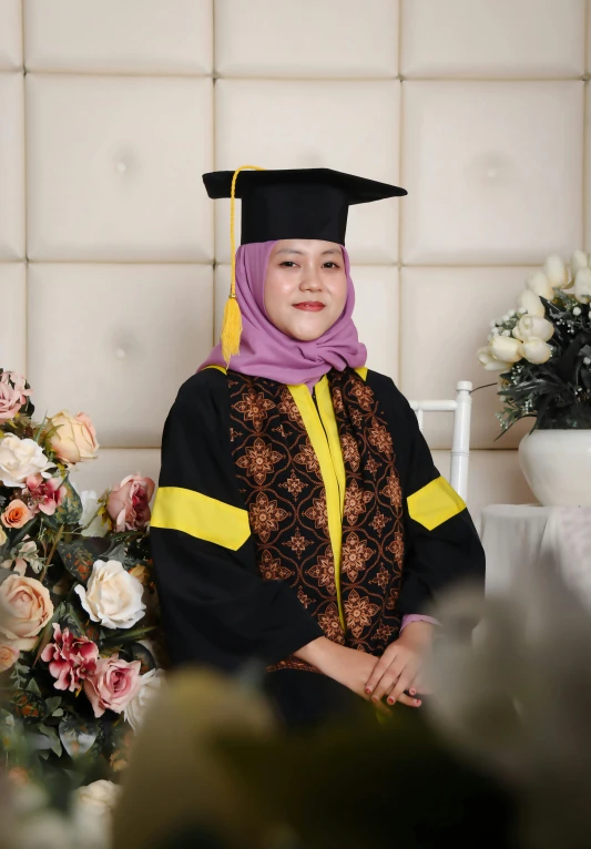 a female in a black graduation gown and yellow and black scarf