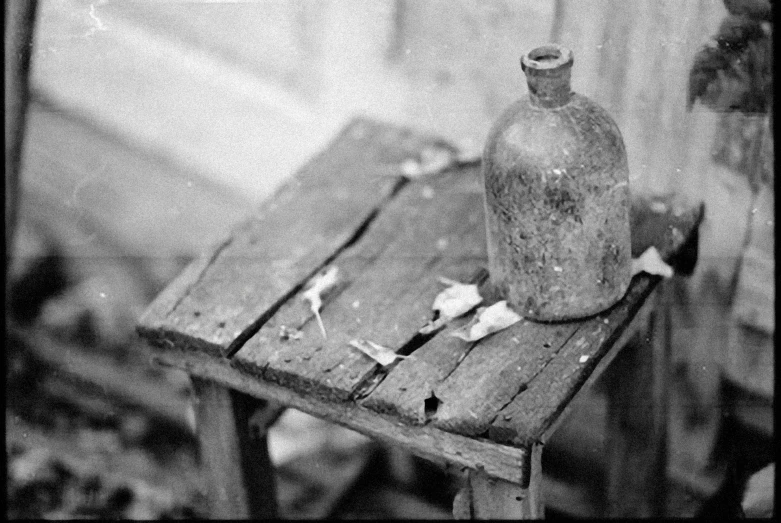 an old wooden bench with a bottle on top