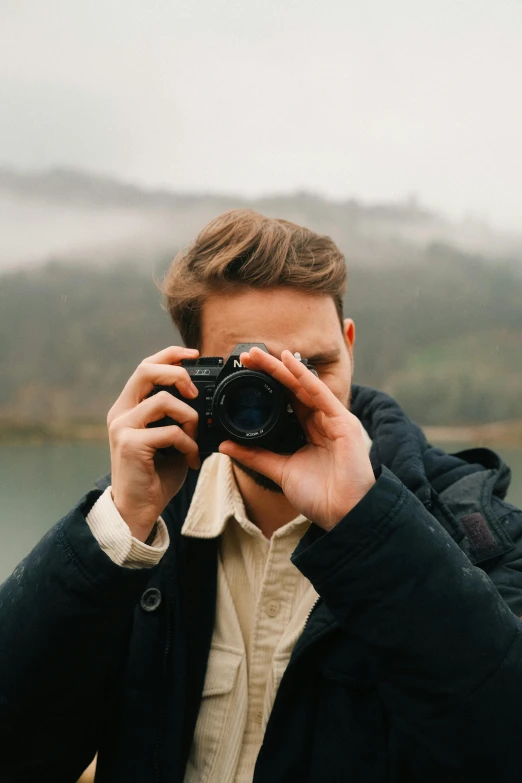 man holding up camera looking at his selfies in front of him