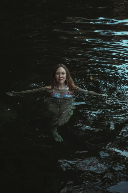 a girl is floating in the water holding a stick