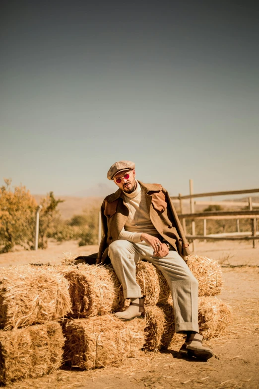 man on hay bale next to wooden fence