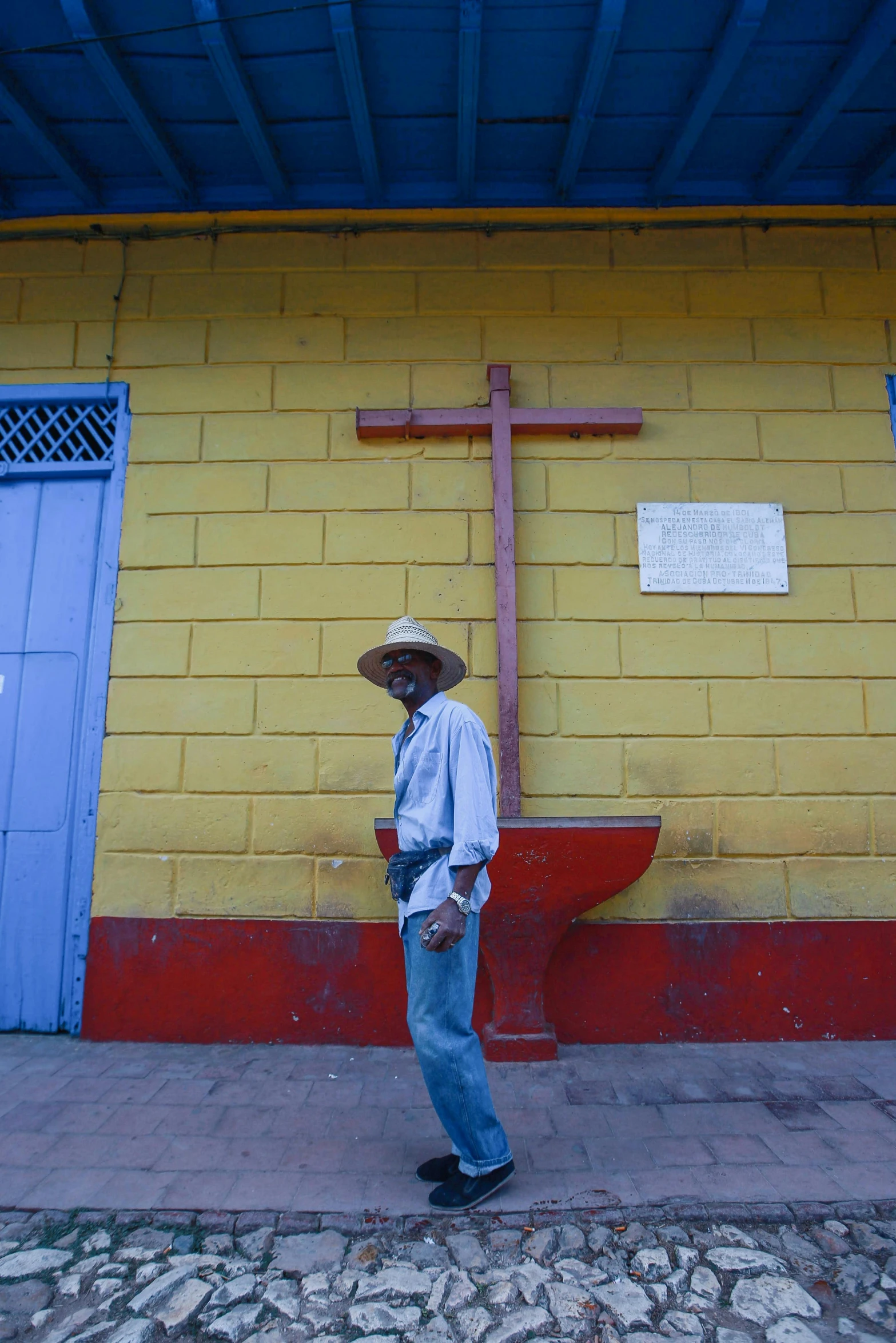 a man standing near a yellow building with a cross on it