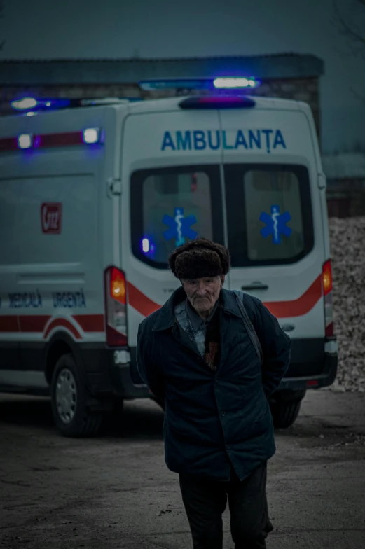 an old man in front of a ambulance is standing