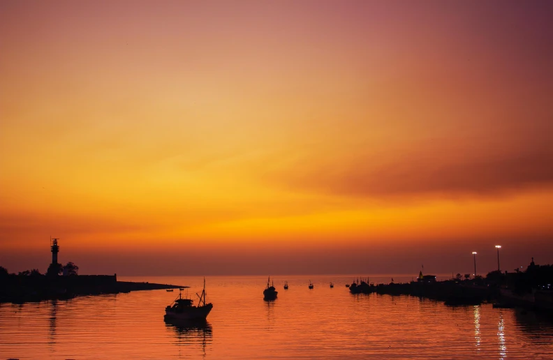 the silhouette of two boats with large sails in the water