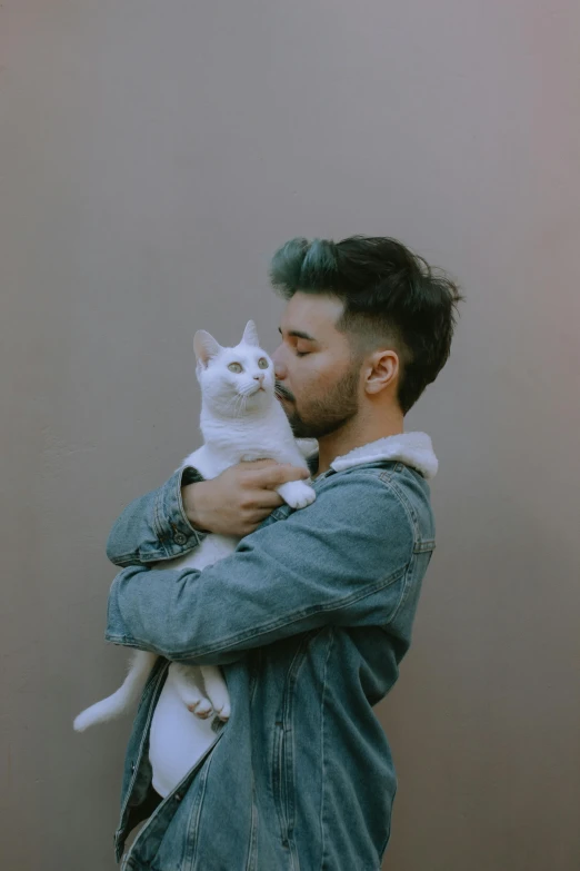 a man holding a white cat up to his face