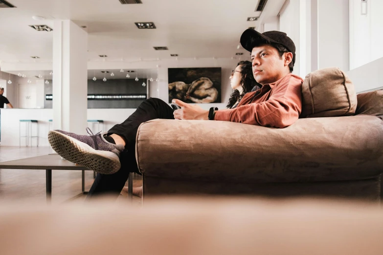 a young man sitting on a couch talking on a cell phone