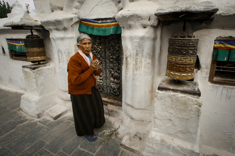 the old woman stands in front of her home