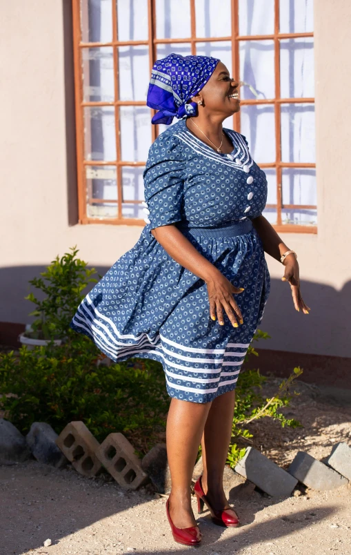 a lady in a blue and white dress smiles and waves