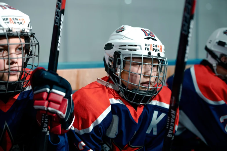 three lacrosse players in their uniforms on the ice