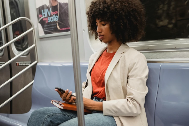 the woman on the subway is texting and holding her phone