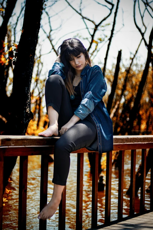 the girl in the blue jacket is posing on the bridge