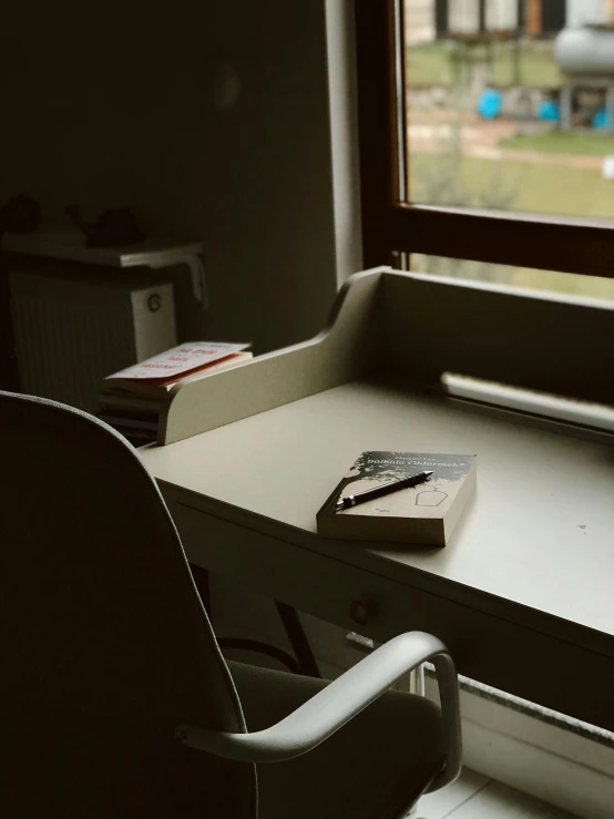 a desk with a book, pen and paper on it