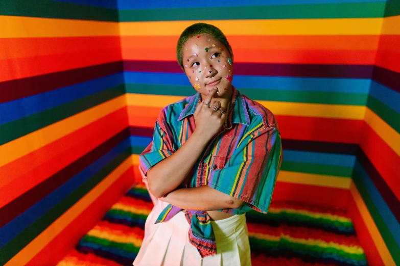 a young man poses with his hands together in a colorful room with multi - colored walls