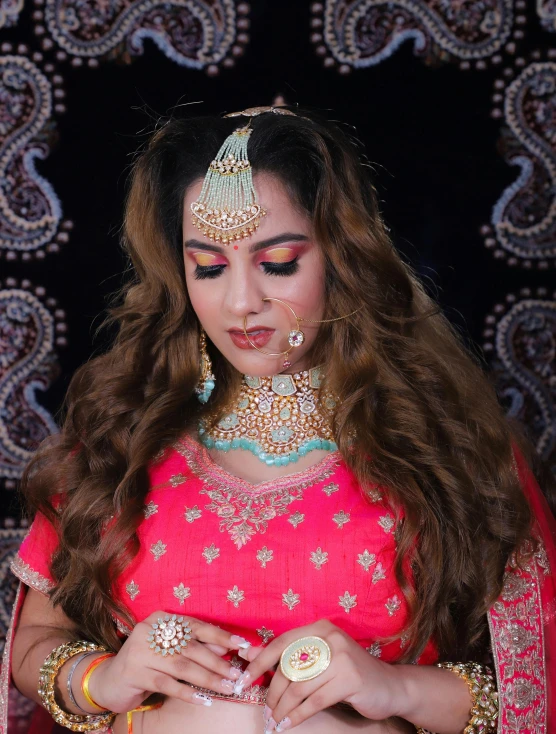 a woman wearing a pink and gold outfit with jewelry on her shoulder