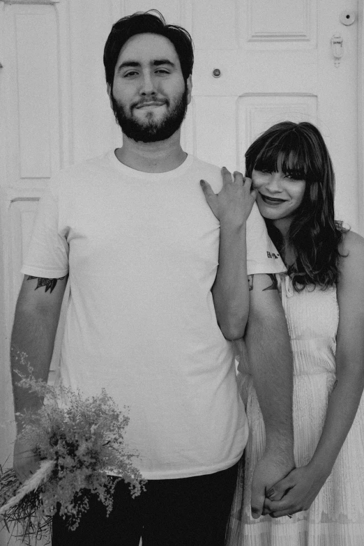 two people pose for a picture in front of white painted wall