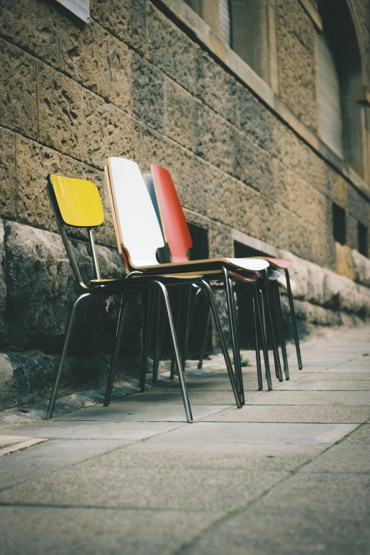 four chairs are lined up against a brick wall