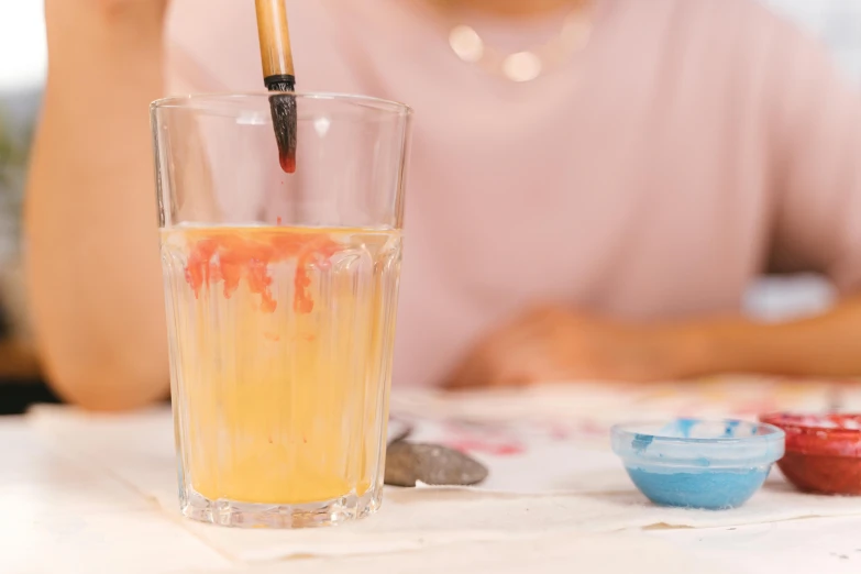 a person is sitting and drinking from a glass with a straw