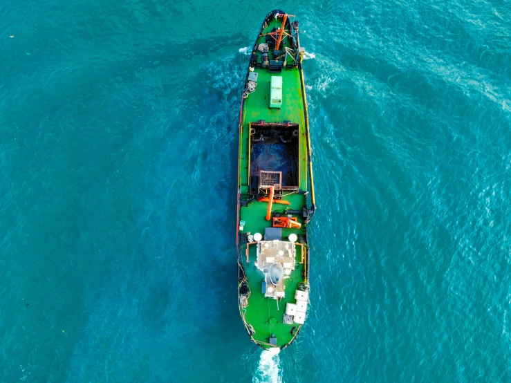 a green and white boat floating on top of the ocean