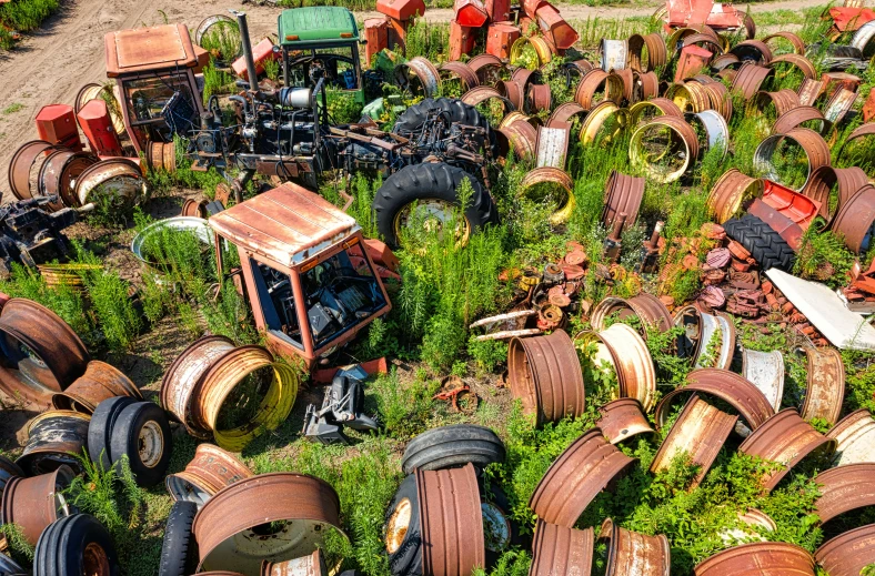 old tractor tires and other machinery lie in the dirt