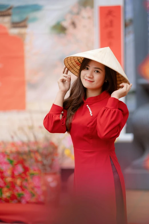 the woman in the chinese style dress and hat is posing for the camera