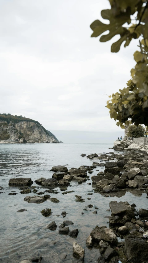 a couple walks along a rocky shoreline