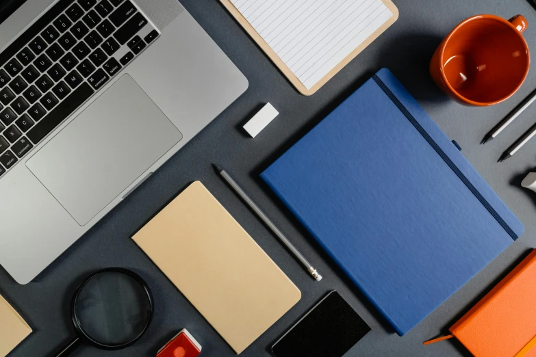 a bunch of different types of pens, a laptop and notebook