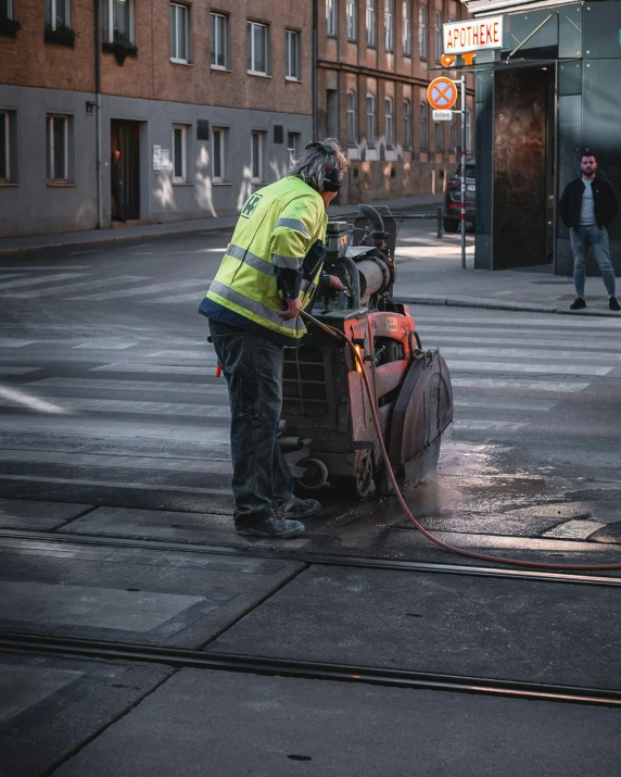 a worker spraying down water on a street corner