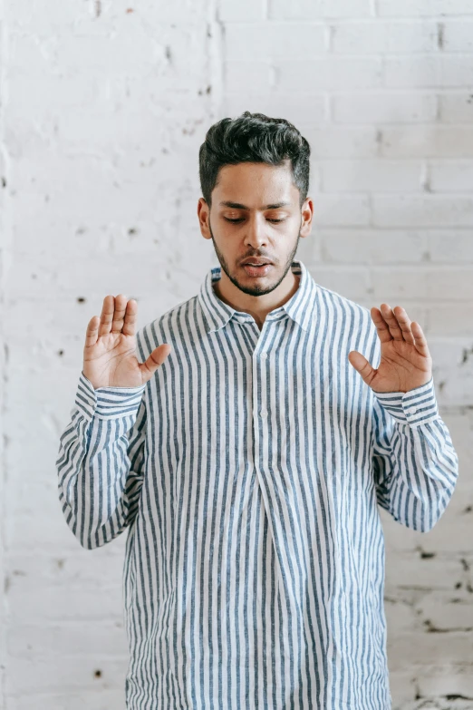 a man in a striped shirt has his hands together