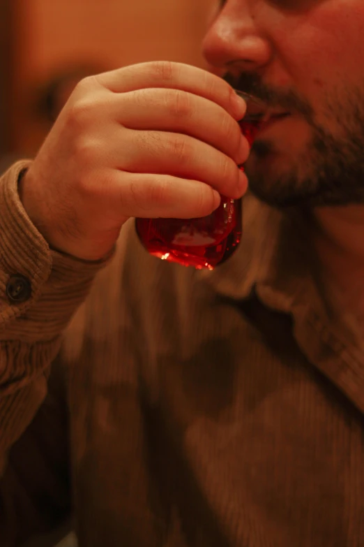 a man sipping a glass of wine with his finger