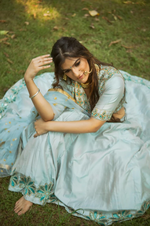 a woman in blue sitting on the ground in front of grass