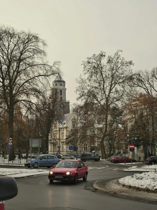 a red car driving down a snow covered street