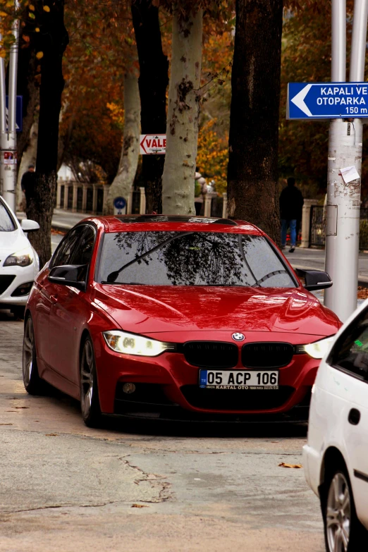 a red bmw sits parked in front of white car