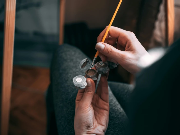 a person holds a pencil and a coin in her hand