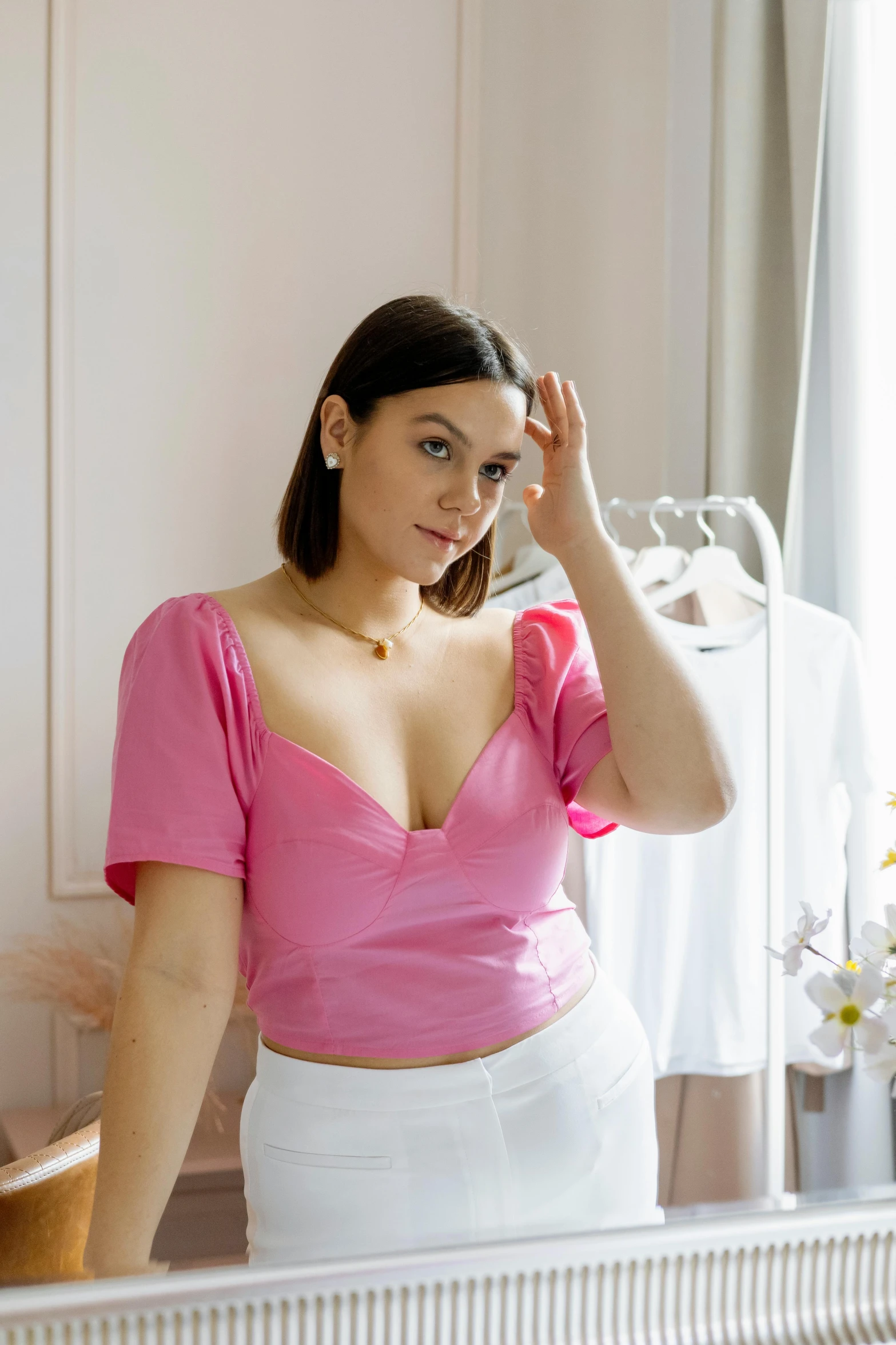 a young woman adjusts her hair in front of a mirror