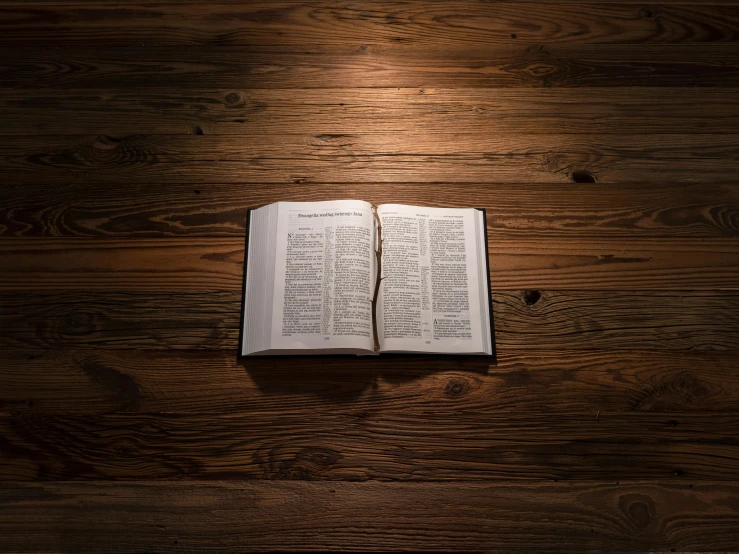 a open bible laying on top of a wooden table