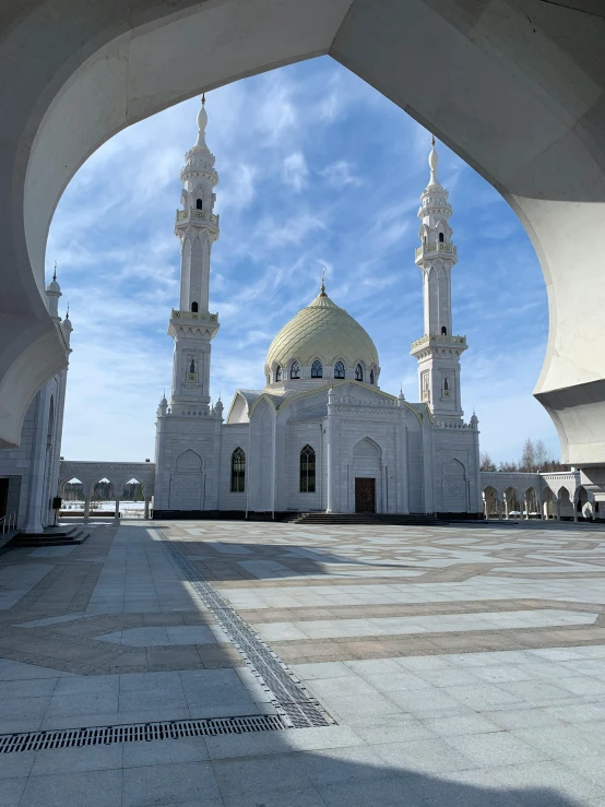 a tall white building that has a few smaller buildings inside