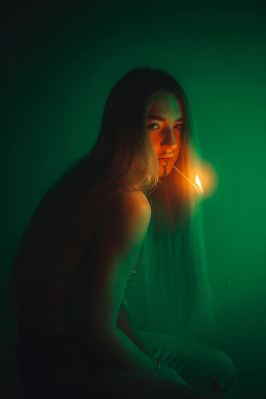 young woman sitting in the dark with a lit candle