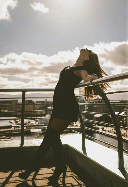 a girl in high heels standing on the railing of a tall building