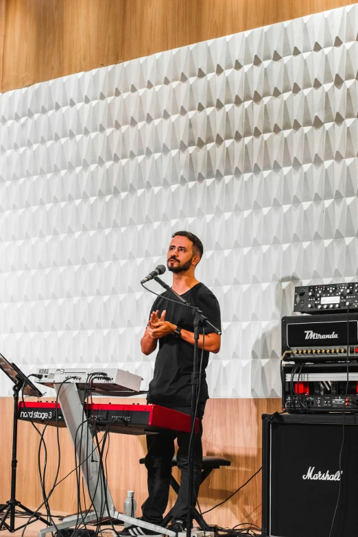 a man in black shirt and headphones standing in front of a microphone