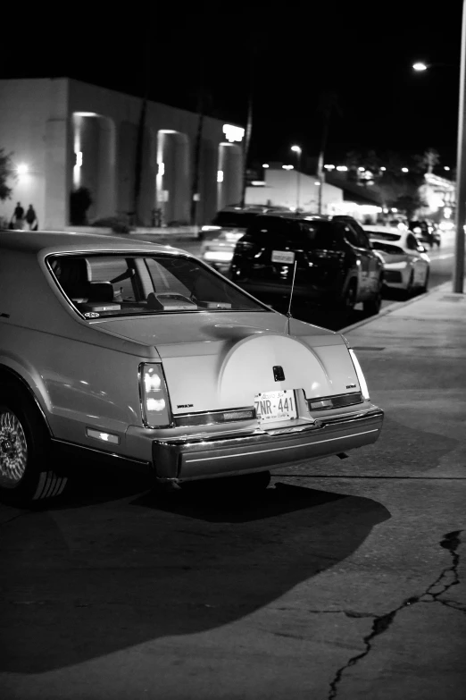 a car sits on the street as traffic passes by