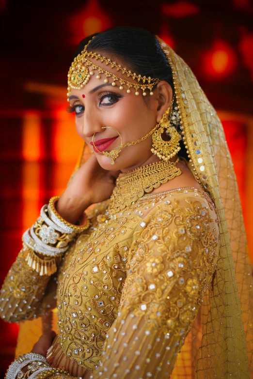 a bride in traditional indian garb stands with her hands on her chin