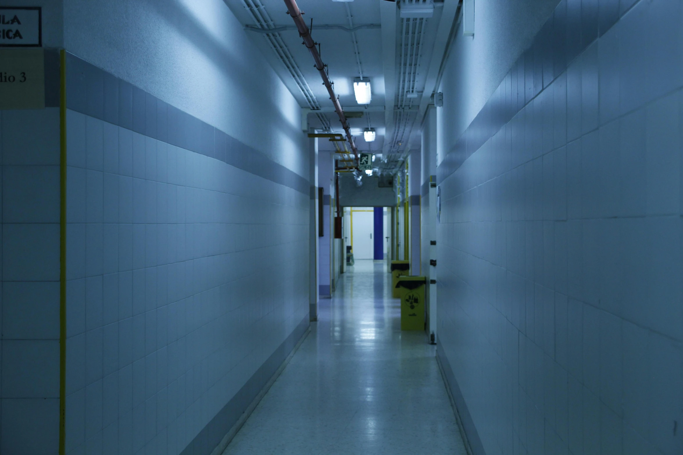 an empty blue hallway leading to some toilets