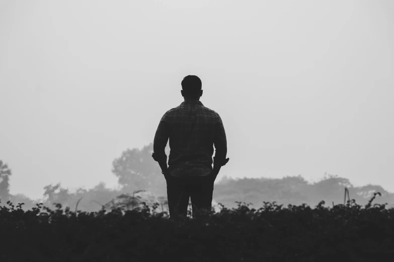 a man standing on the edge of a field looking at a plane