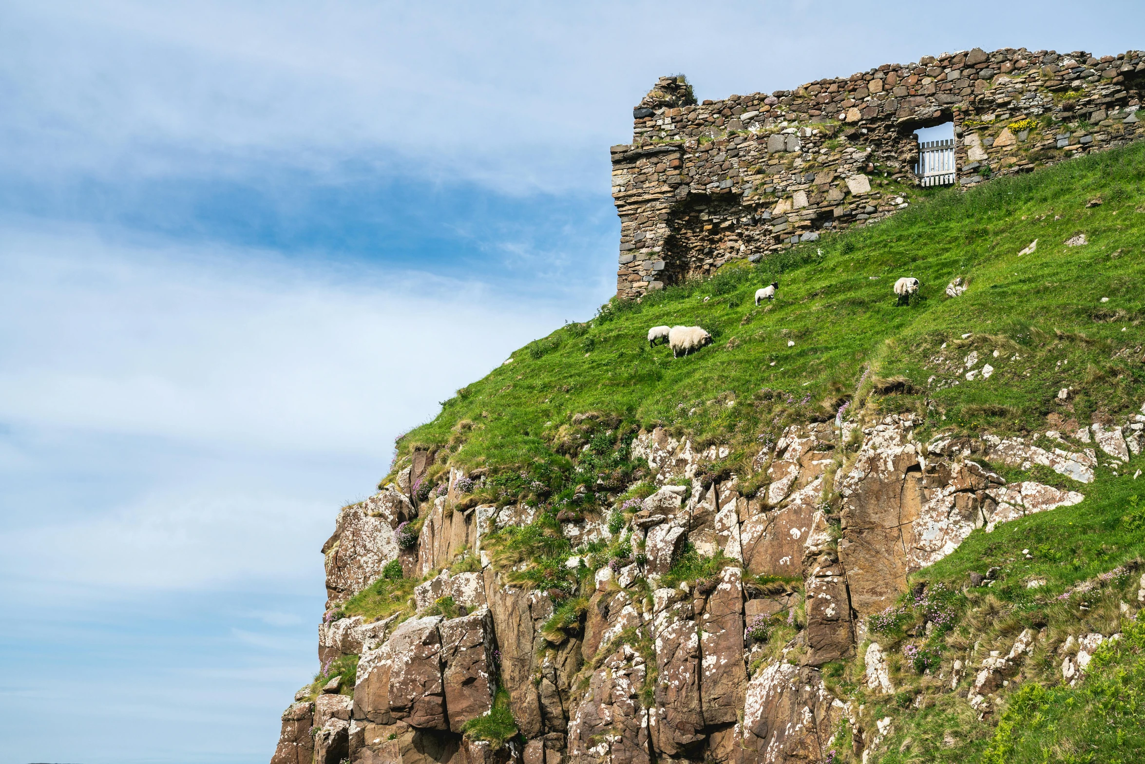 a stone cliff with sheep on it