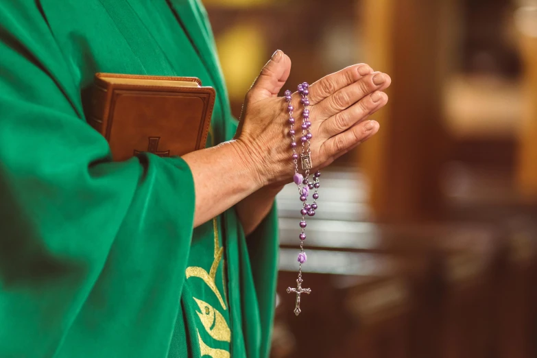 woman in a priest's outfit is holding the rosary