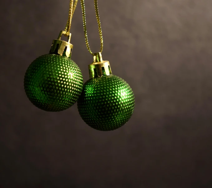 two green balls with gold chains hung from a chain